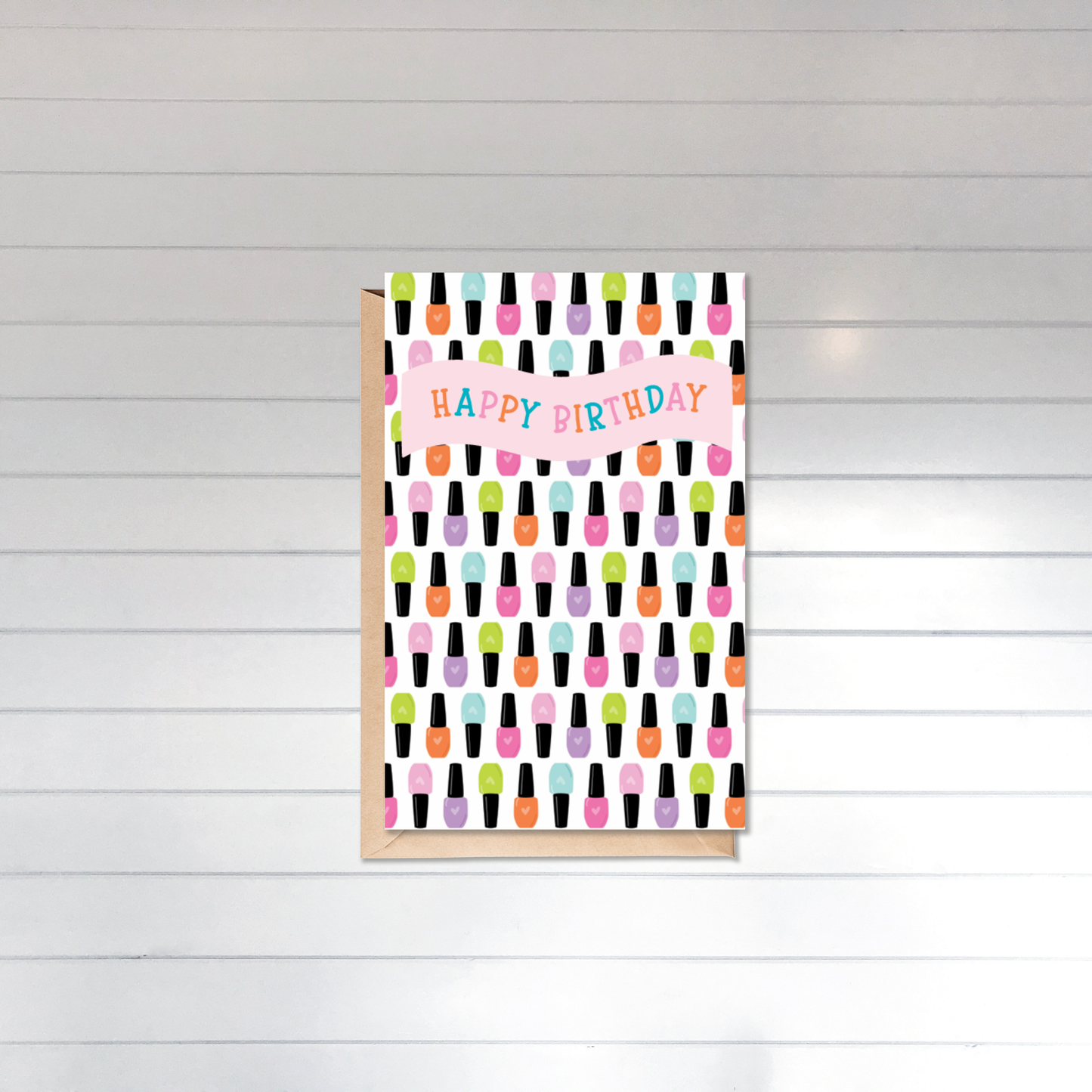 Greeting card with colorful nail polish pattern and 'Happy Birthday' text on a wooden surface.