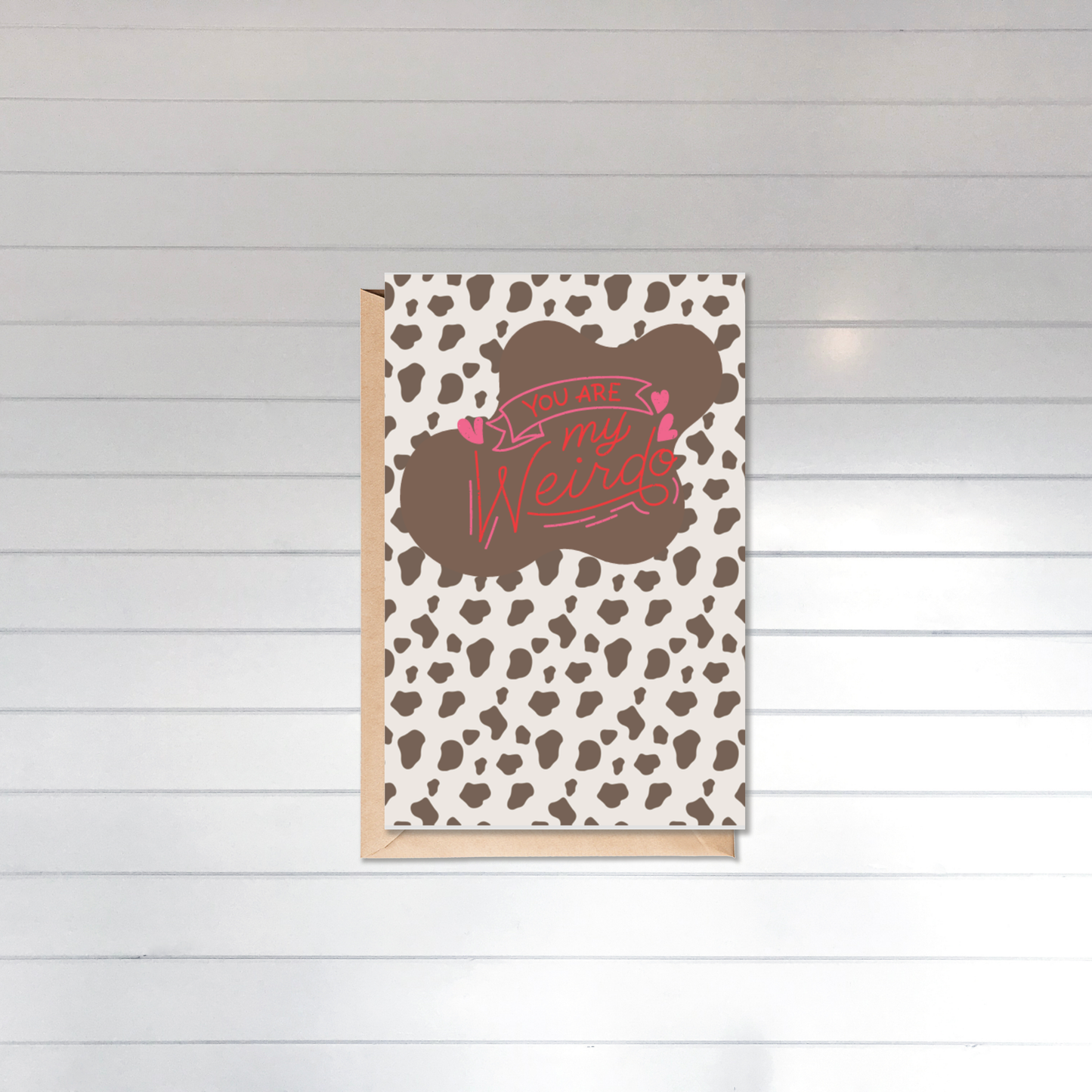 Card with cow print pattern and text on a wooden surface