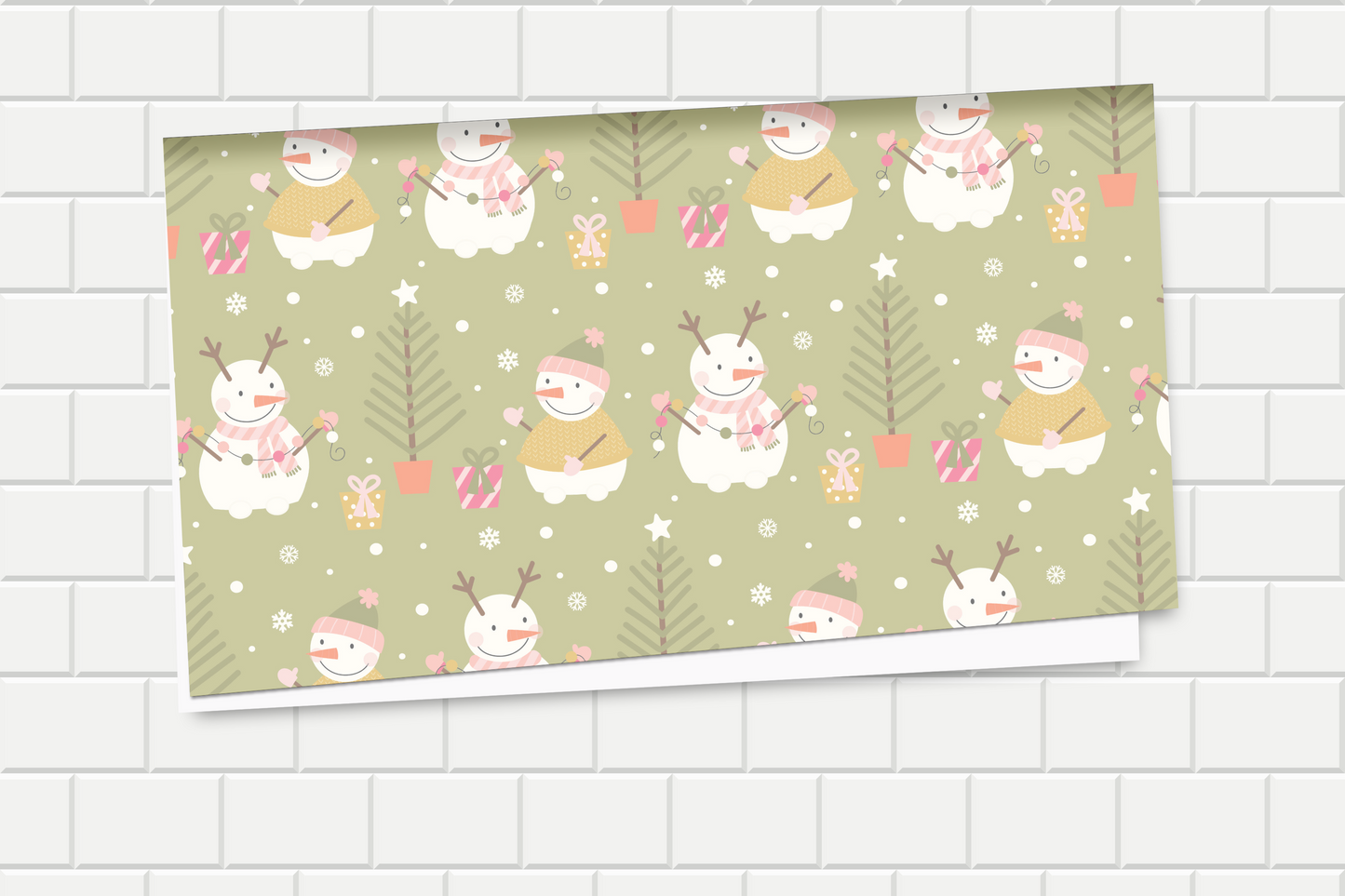 Decorative wrapping paper with cartoon snowmen and trees on a green background, displayed on a tiled wall.