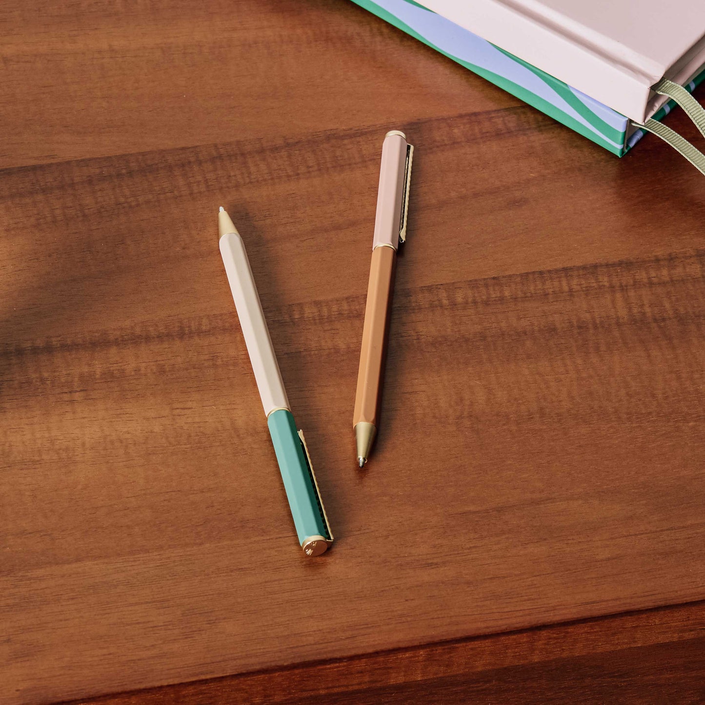 Two pens with wooden and green accents on a wooden surface